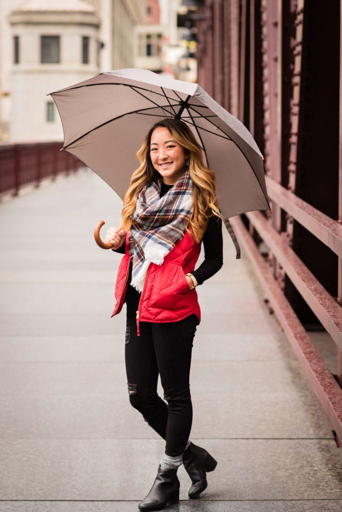Girl in black pants and red vest holding umbrella