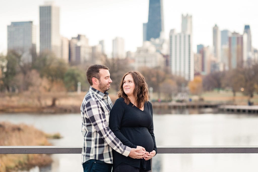 woman with husband maternity pictures Lincoln park nature boardwalk bridge with chicago skyline in the background