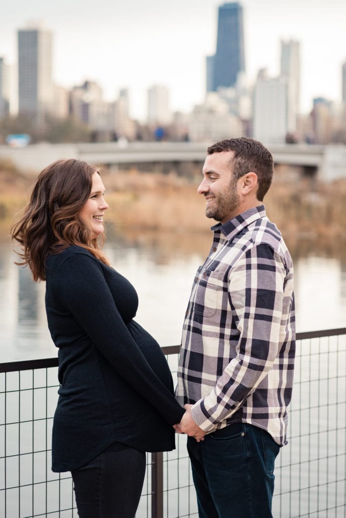 Maternity pictures in chicago girl in black facing husband at Lincoln park nature boardwalk