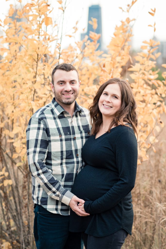 Husband and wife smiling at the camera during maternity photo shoot at Lincoln park nature boardwalk