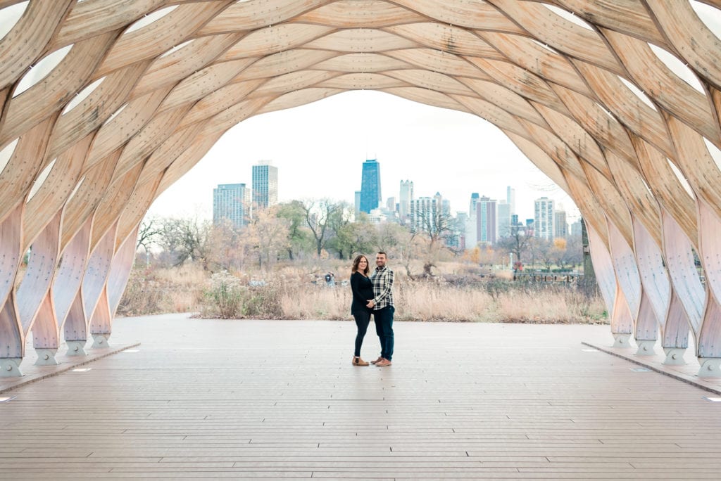 husband and wife standing under the honey comb at Lincoln park nature boardwalk maternity pictures